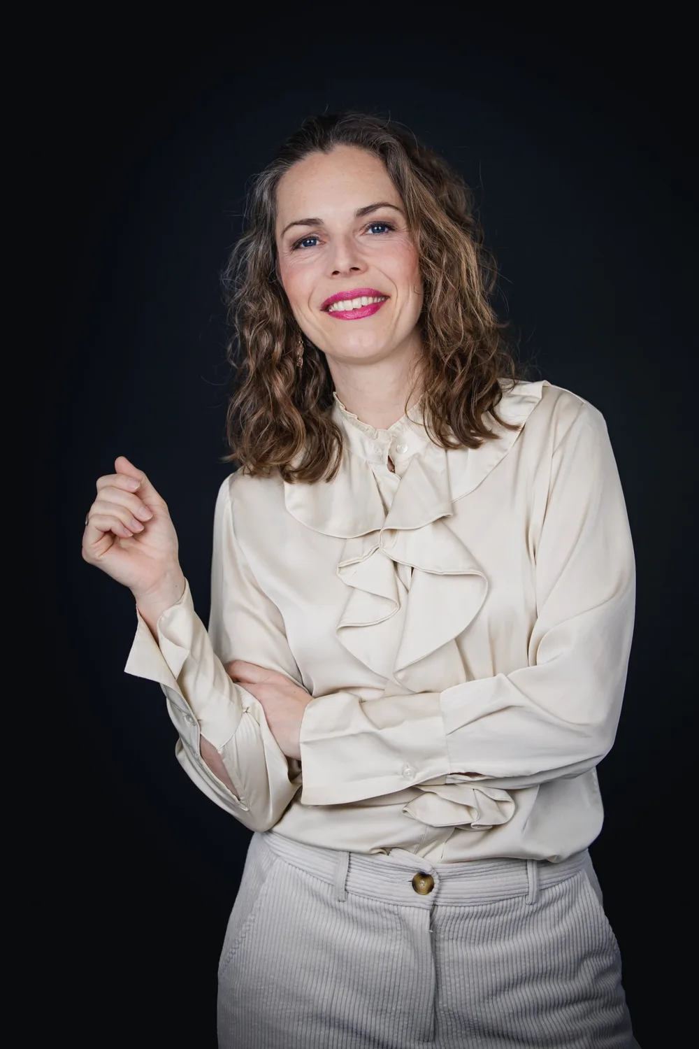 Juliane Klüß in heller Bluse vor dunklem Hintergrund, sie lächelt selbstbewusst